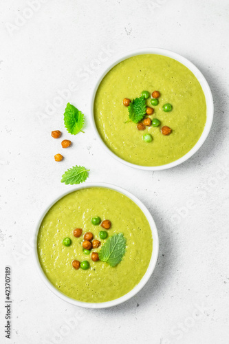 Fresh light spring green pea soup in bowls. Top view, space for text, flat lay.