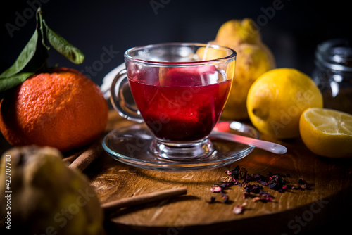 cup of fruit tea on a wooden table. red tea together with its ingredients seen from above