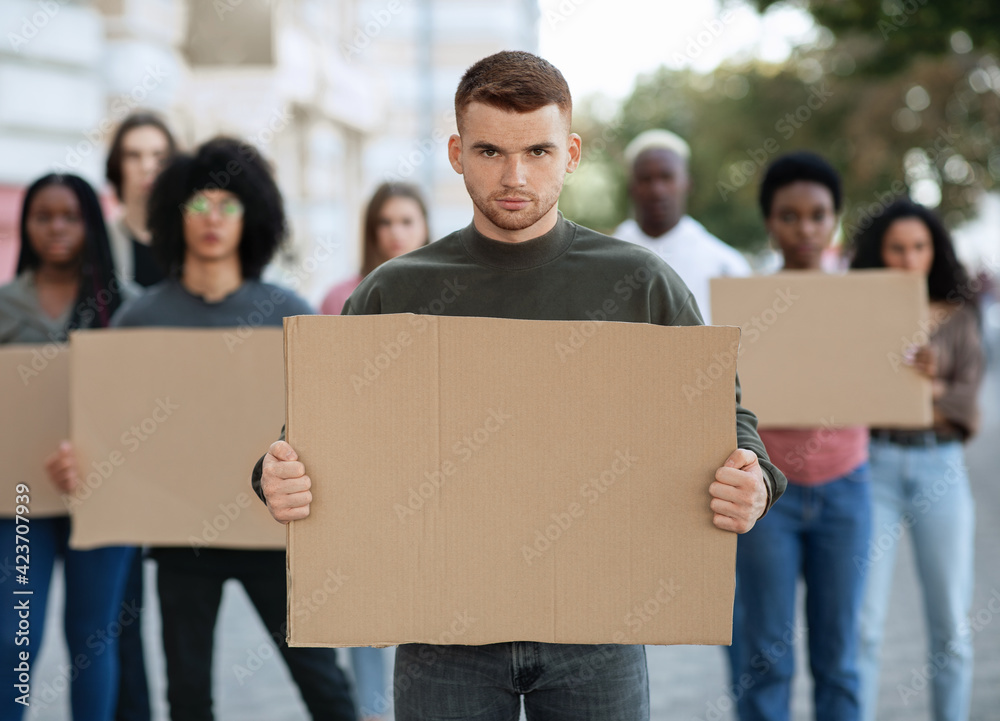 Confident guy leading a group of demonstrators with placards
