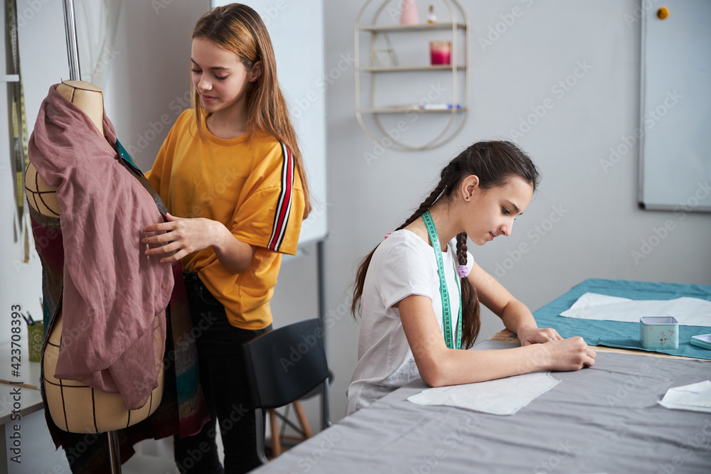 Obraz premium Two charming girls working in sewing workshop