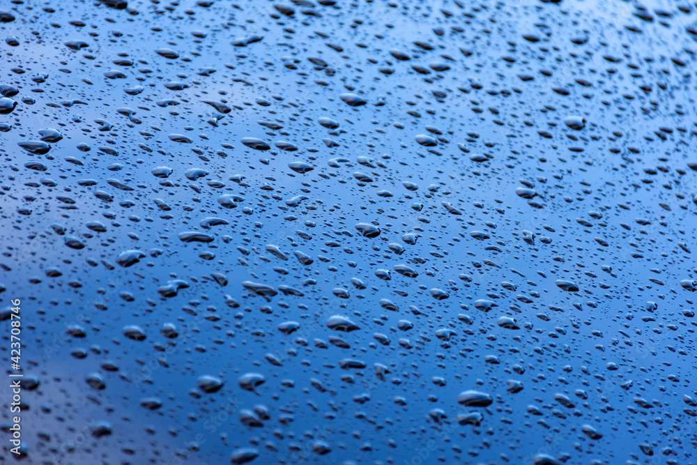 Raindrops texture on the glass of a blue car. Soft focus on the edges Raindrops texture on the glass of a blue car. Soft focus on the edges