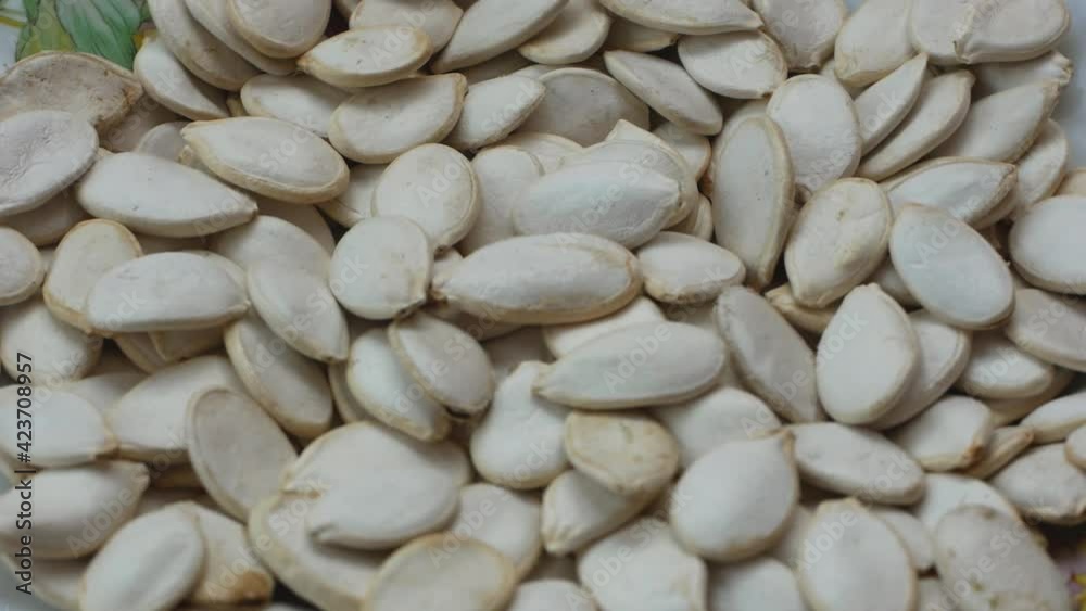 Close-up of a bunch of white pumpkin seeds rotating. Falling pumpkin seeds. Sources of vitamins in pumpkin seeds. Selective focus, shallow depth of field Close-up of a bunch of white pumpkin seeds rotating. Falling pumpkin seeds. Sources of vitamins in pumpkin seeds. Selective focus, shallow depth of field