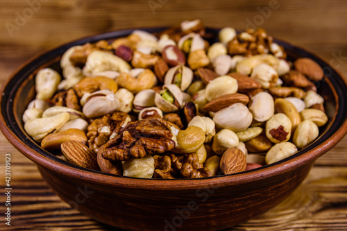 Various nuts (almond, cashew, hazelnut, pistachio, walnut) in ceramic plate on a wooden table. Vegetarian meal. Healthy eating concept