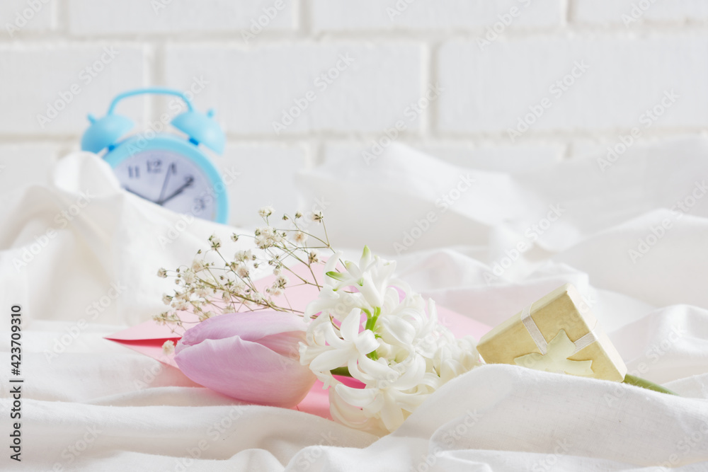 blue alarm clock, flowers on the bed, spring morning mood concept, beautiful tulips and hyacinth in the spring morning blue alarm clock, flowers on the bed, spring morning mood concept, beautiful tulips and hyacinth in the spring morning