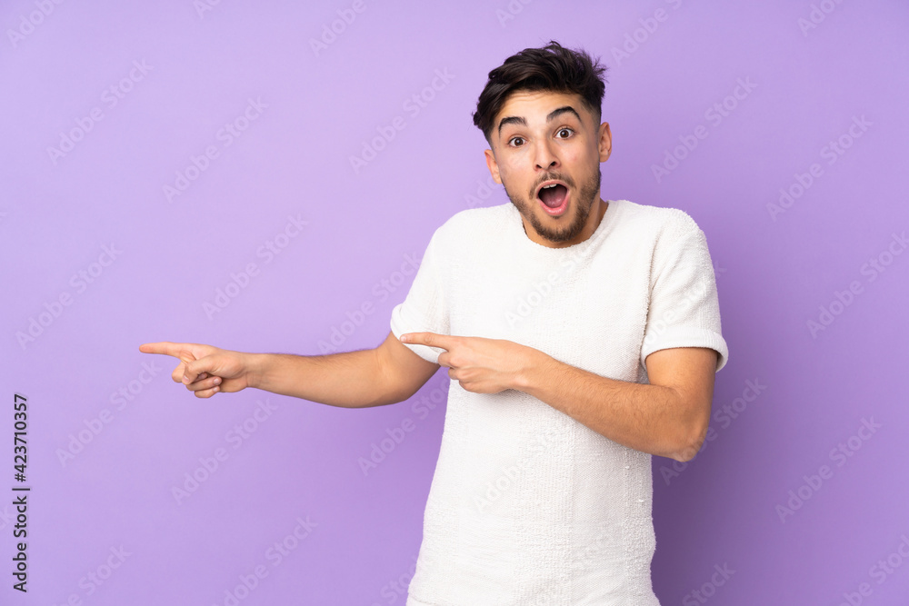 Arabian handsome man over isolated background surprised and pointing side Arabian handsome man over isolated background surprised and pointing side