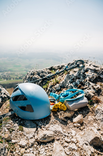 Ferrata climbing equipment. Via Ferrata set with two lanyards with carabiners, helmet with the steel cable in the background. Gear on the cliff at the top of the mountain.