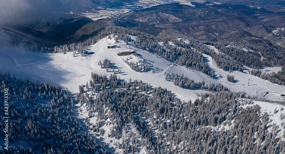 Obraz premium Aerial view of Poiana Brasov ski resort from Postavaru Mountains in Romania. Landmark of winter sports.