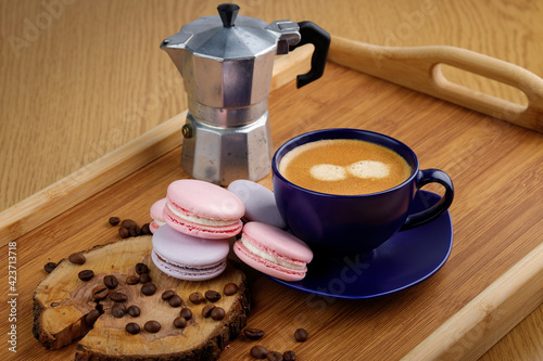 Cup of coffee, macaroons and coffee beans on a platter and geyser coffee maker on a wooden tray