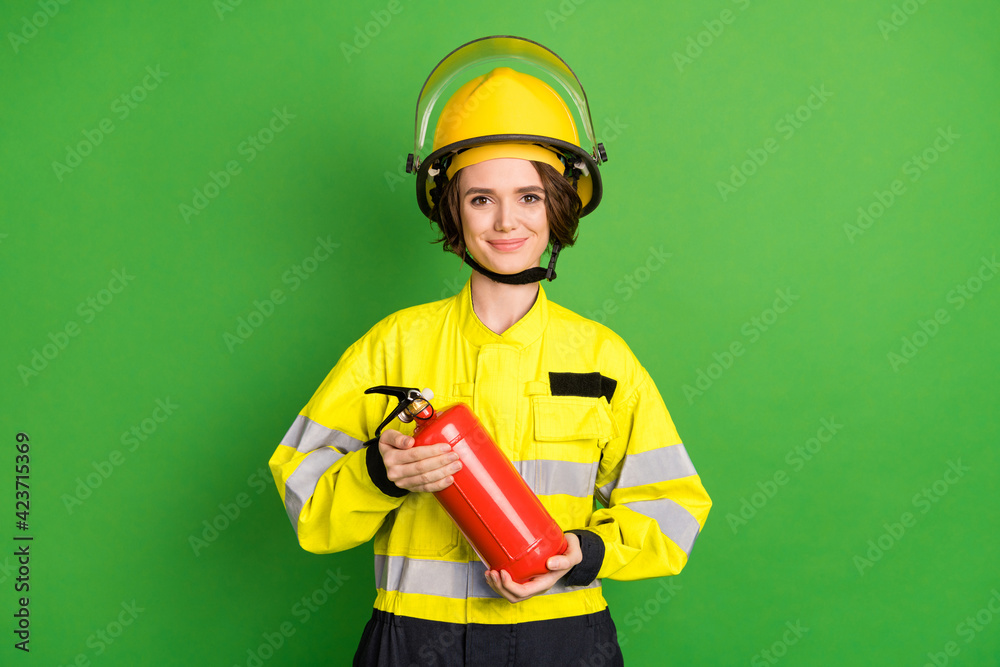 Photo of positive sweet young firewoman dressed yellow uniform helmet extinguishing smiling isolated green color background Photo of positive sweet young firewoman dressed yellow uniform helmet extinguishing smiling isolated green color background