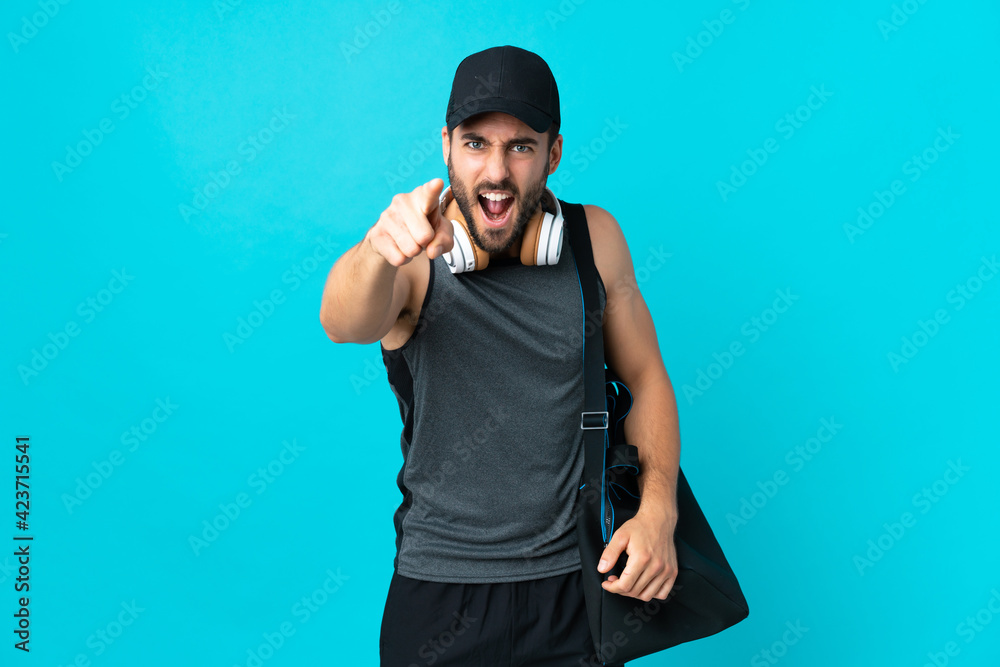 Fototapeta premium Young sport man with sport bag isolated on blue background frustrated and pointing to the front