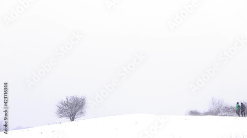 Two hikers walk on the snow near forest path in winter