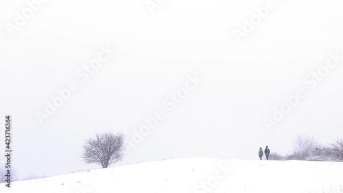 Two hikers walk on the snow near forest path in winter