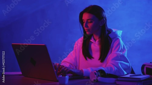 Woman working with a computer on a colorful neon light background