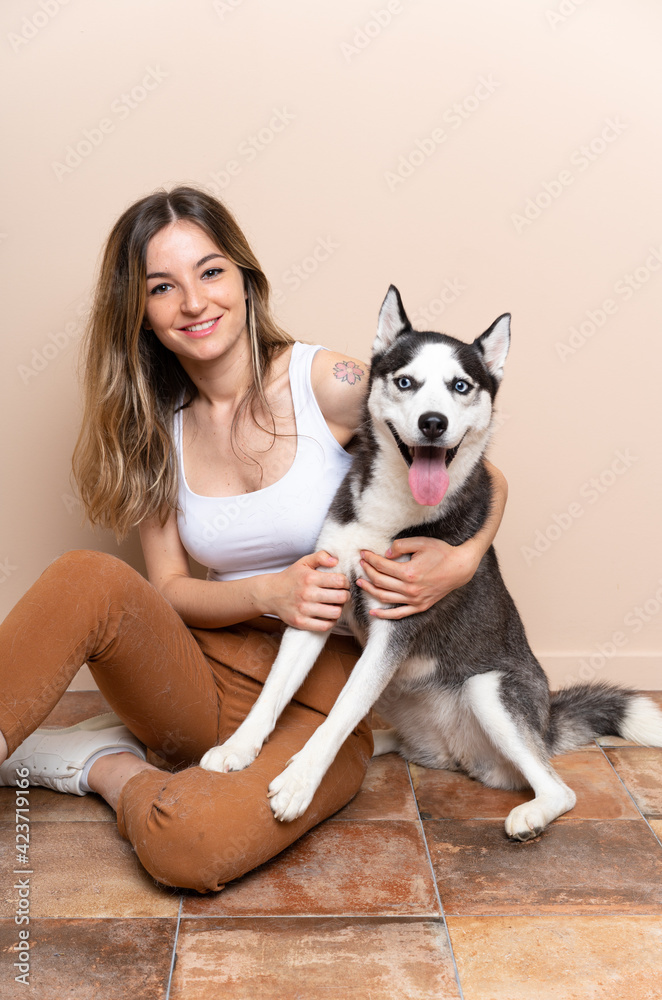 Young pretty woman with her husky dog sitting in the floor at indoors