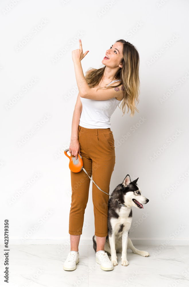 A full length young pretty woman with her dog pointing with the index finger a great idea