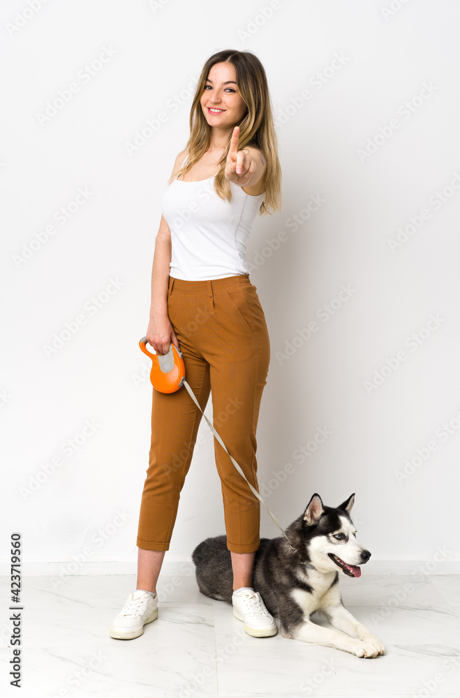 A full length young pretty woman with her dog showing and lifting a finger