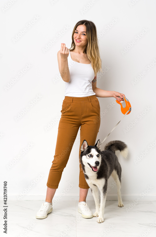 A full length young pretty woman with her dog making money gesture