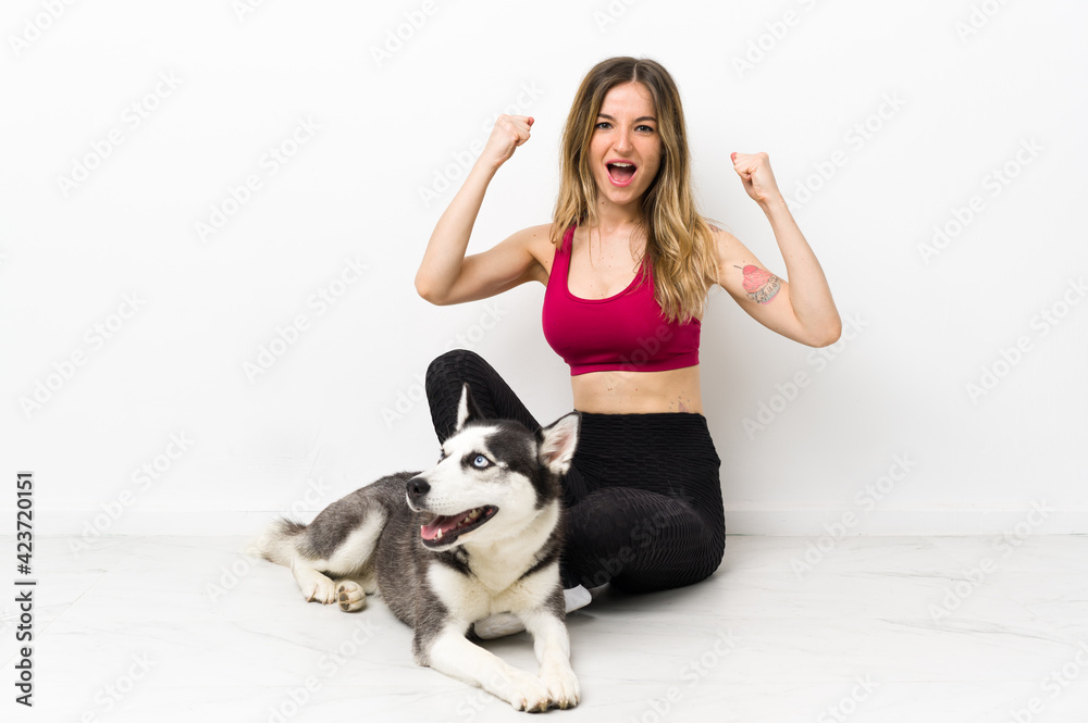 Young sport girl with her dog sitting on the floor celebrating a victory