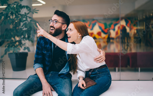 Shocked Caucasian couple in love 20s discussing something feeling amazed during together leisure time, happy impressed male and female in casual clothing wondering during date flirting indoors