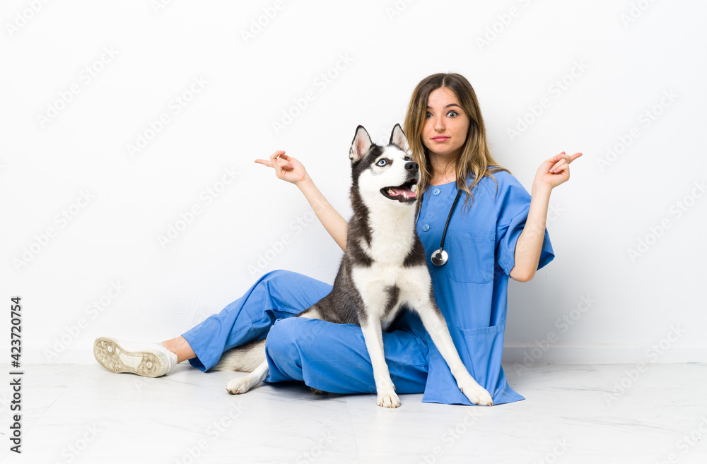 Veterinary doctor with Siberian Husky dog sitting on the floor pointing to the laterals having doubts