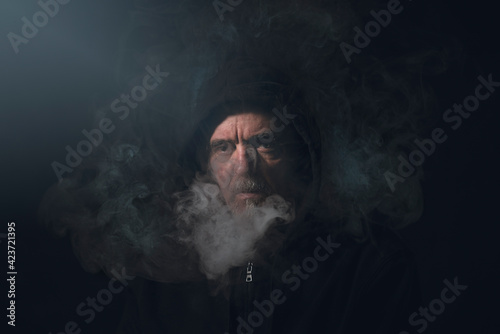 portrait of a man in hoodie with smoke in front of his face