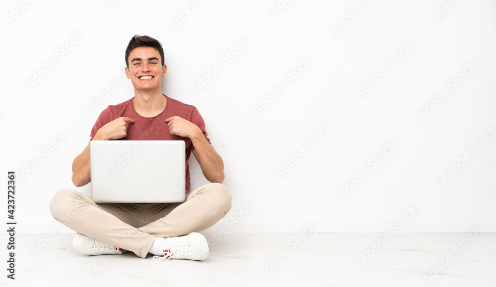 Teenager man sitting on the flor with his laptop with surprise facial expression Teenager man sitting on the flor with his laptop with surprise facial expression