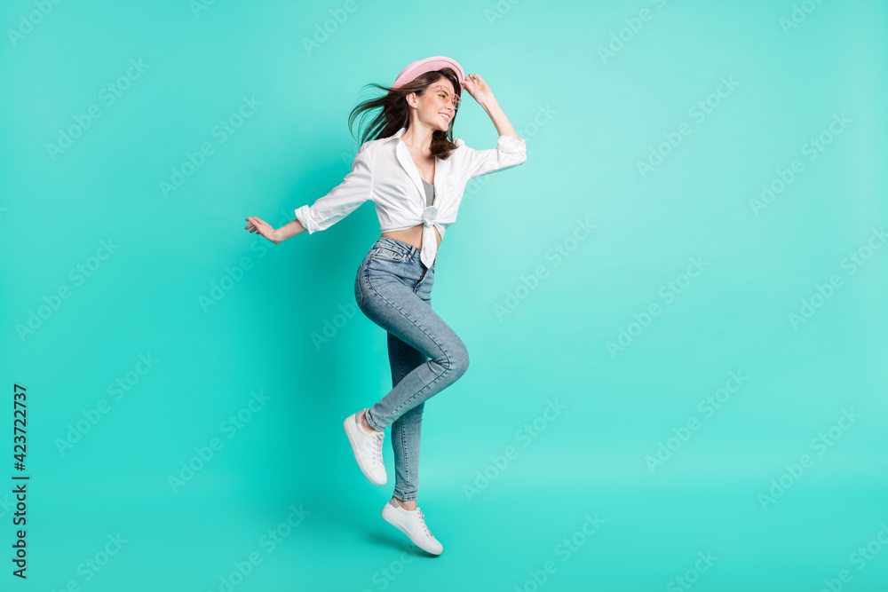 Photo of sweet cute lady wear shirt spectacles arm headwear jumping high looking empty space isolated turquoise color background