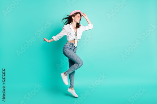 Photo of sweet cute lady wear shirt spectacles arm headwear jumping high looking empty space isolated turquoise color background © deagreez