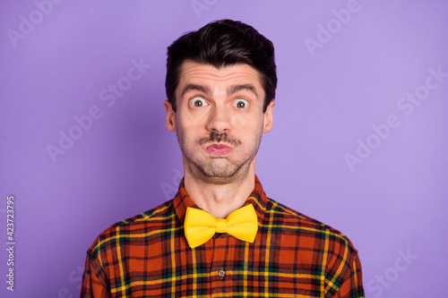 Photo of crazy foolish guy puffed cheeks look camera wear bow tie checkered shirt isolated violet background