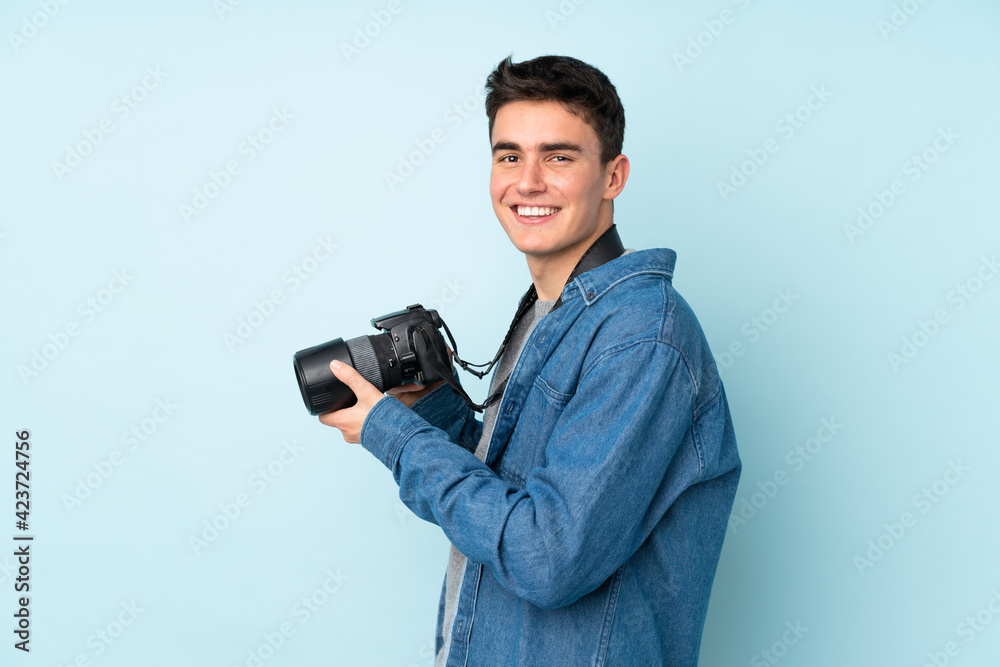 Teenager photographer man isolated on blue background Teenager photographer man isolated on blue background