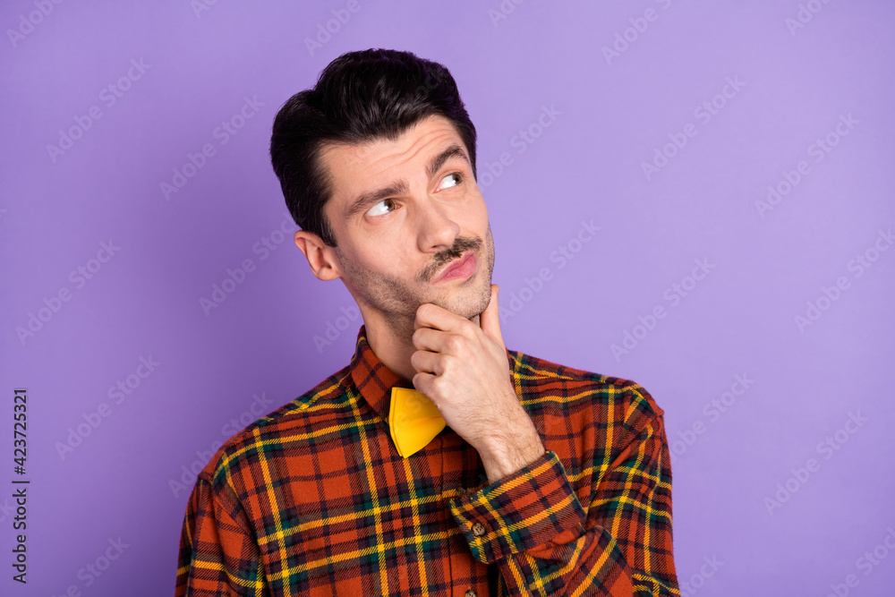 Photo of minded pensive guy finger chin look empty space wear bow tie checkered shirt isolated purple background Photo of minded pensive guy finger chin look empty space wear bow tie checkered shirt isolated purple background
