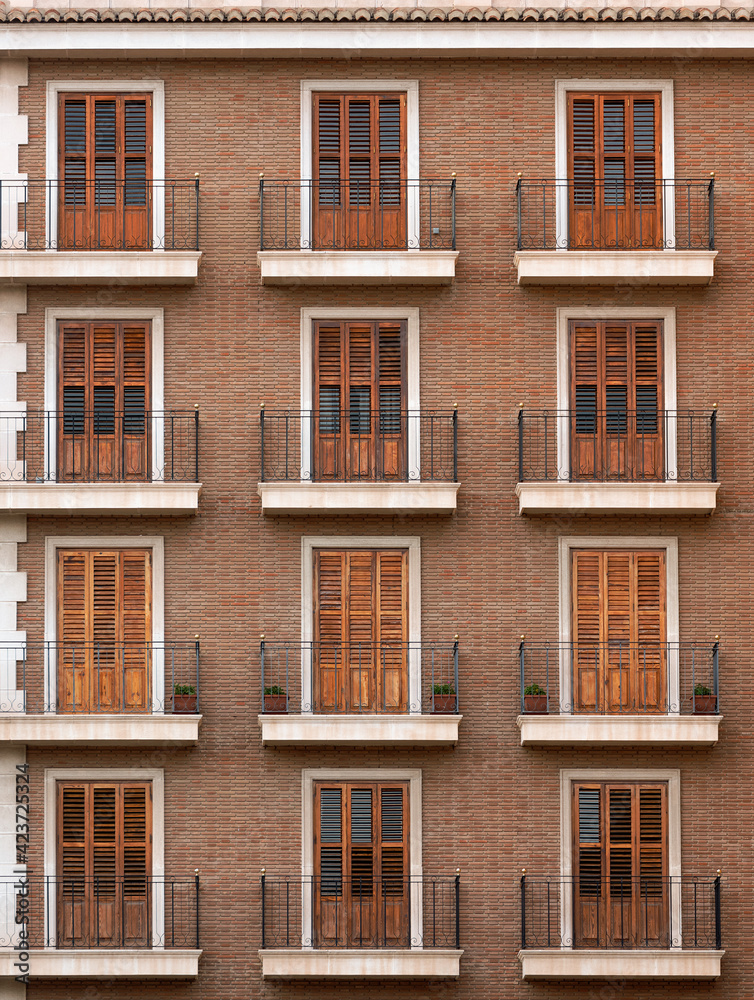 Beautiful facade of a brick building with balconies. Classic European style with shutters