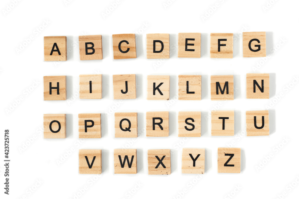 Top view of english alphabet made of square wooden tiles with the English alphabet scattered on a white background with space for text. The concept of thinking development, grammar. Top view of english alphabet made of square wooden tiles with the English alphabet scattered on a white background with space for text. The concept of thinking development, grammar.