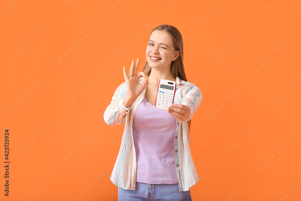 Young woman with calculator showing OK gesture on color background Young woman with calculator showing OK gesture on color background