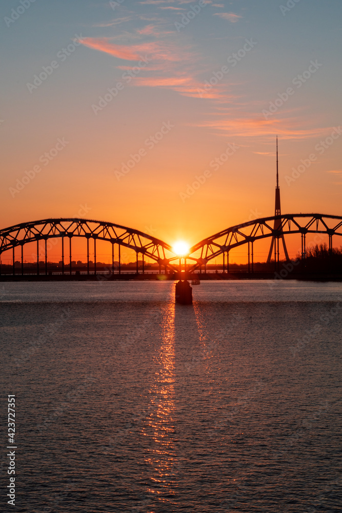 Colorful sunrise over the Daugava river and the Railway bridge with the tallest tower in the European Union - Radio and TV tower in Riga, Latvia Colorful sunrise over the Daugava river and the Railway bridge with the tallest tower in the European Union - Radio and TV tower in Riga, Latvia
