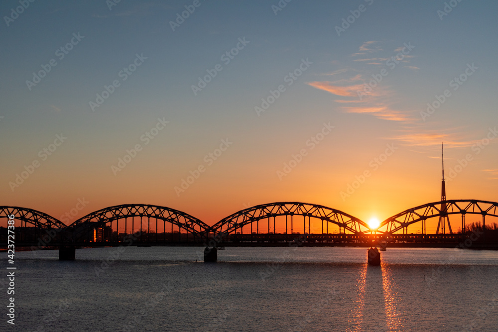 Colorful sunrise over the Daugava river and the Railway bridge with the tallest tower in the European Union - Radio and TV tower in Riga, Latvia