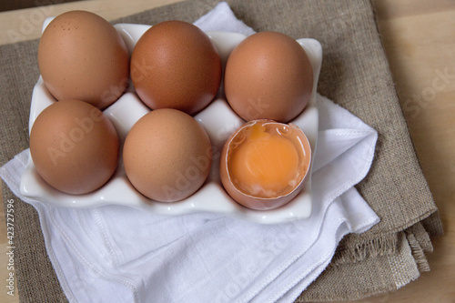 Six chicken eggs in a white stand on a wooden table