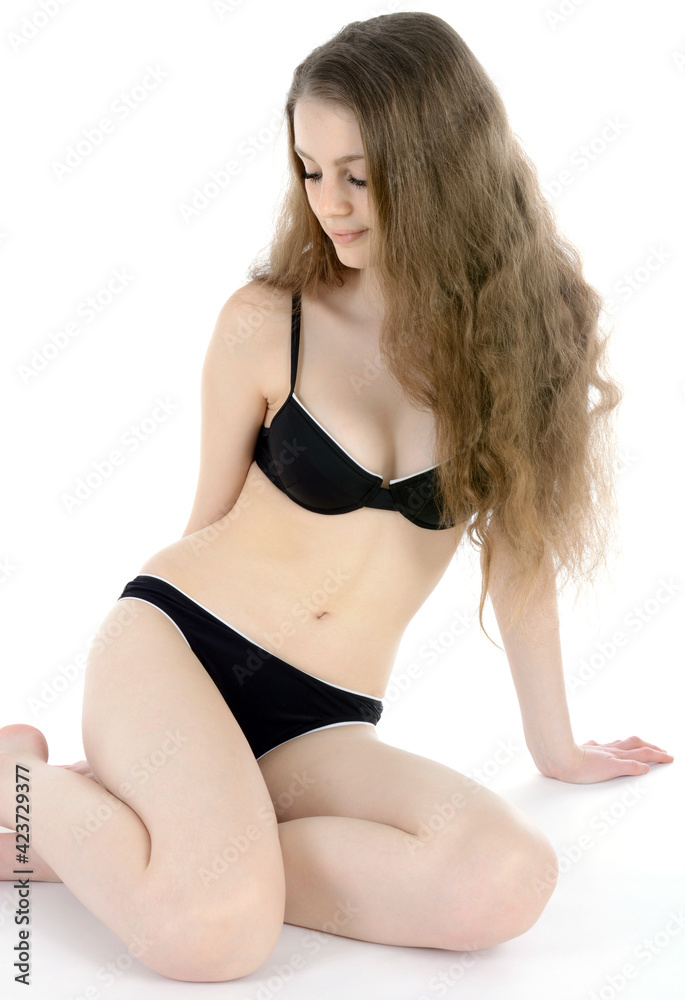 Slim sporty teen girl wearing a black bikini in studio isolated on white  Stock Photo