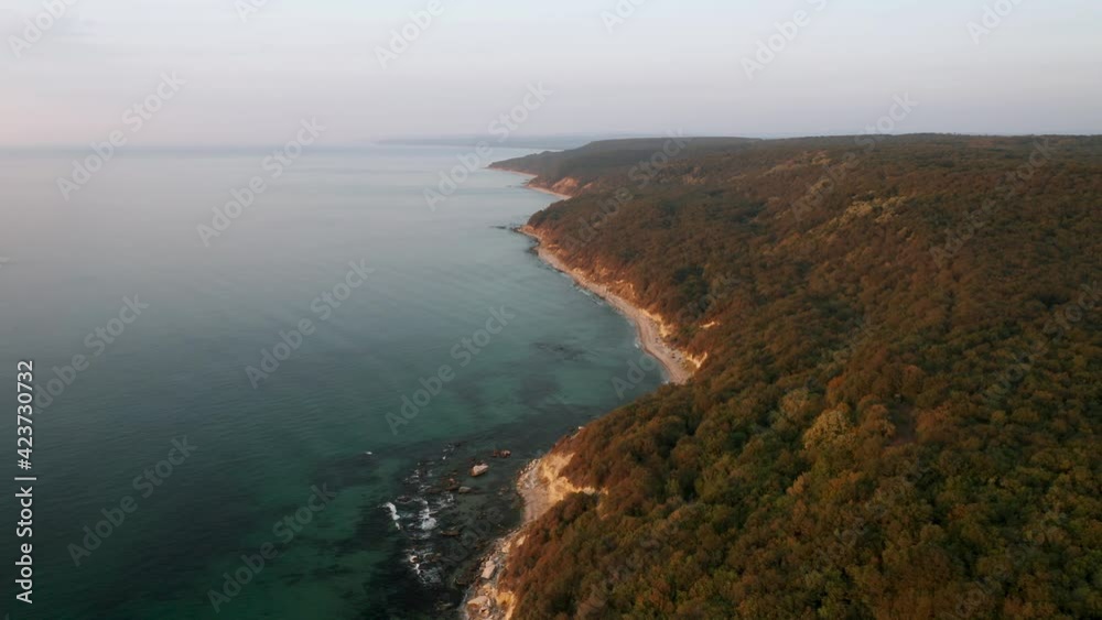 Drone flight above a picturesque rocky coastline with endless sandy beach and overgrown hills in the morning Drone flight above a picturesque rocky coastline with endless sandy beach and overgrown hills in the morning