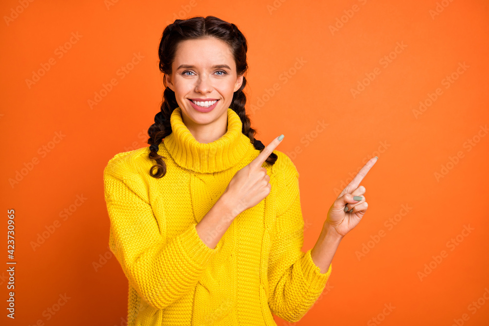 Portrait of brown hair optimistic girl point empty space wear yellow sweater isolated on orange color background Portrait of brown hair optimistic girl point empty space wear yellow sweater isolated on orange color background