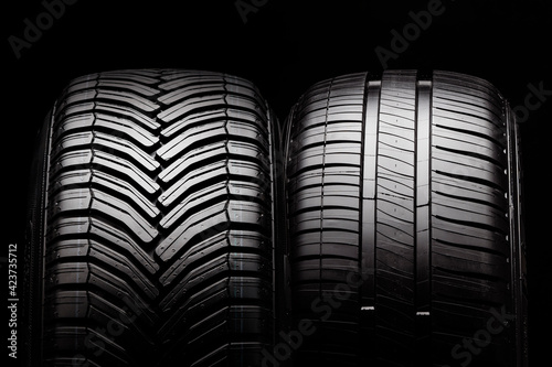 two new summer and all-season tires close-up on a black background photo