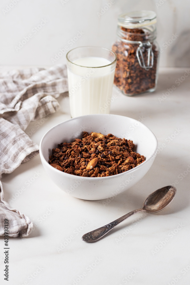 Homemade chocolate granola in a white plate with milk on a light background. Healthy breakfast Homemade chocolate granola in a white plate with milk on a light background. Healthy breakfast