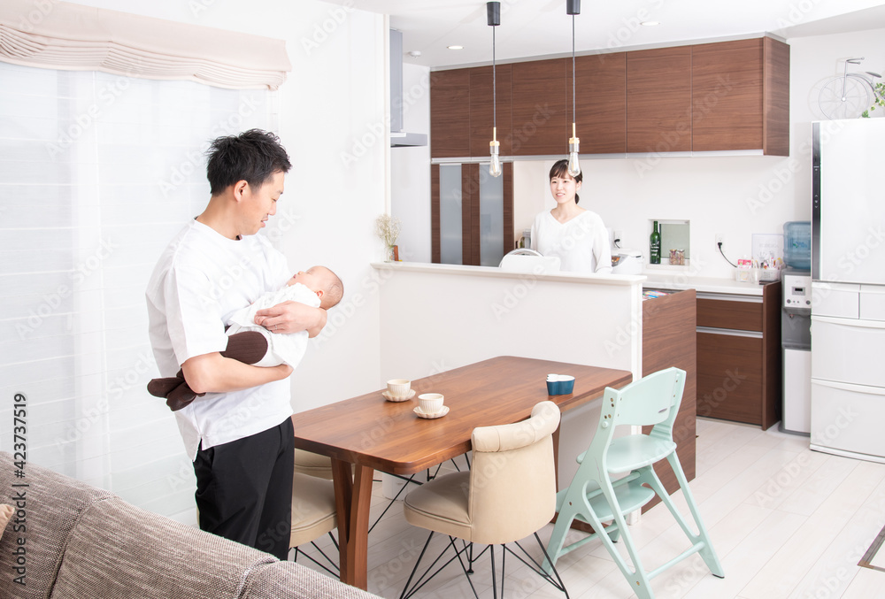 赤ちゃんを抱っこする父親と見守る母親 赤ちゃんを抱っこする父親と見守る母親