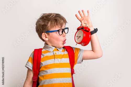 Picture of shocked little boy holding clock alarm. Set up alarm clock. Child hold red clock. It is never too late. Define your own rhythm of life. Happy hours concept. Schedule and timing.
