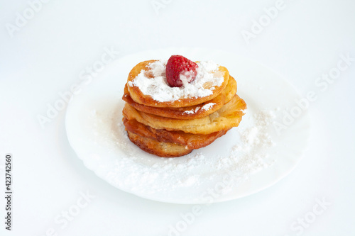Pancakes with powdered sugar and strawberry on a plate, isolated on a white background