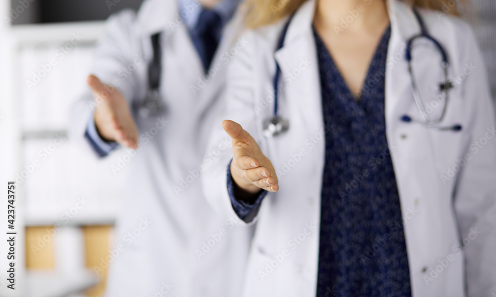 Two doctors standing and offering helping hand for shaking hand or saving life. Medical help, countering viral infection and medicine concept Two doctors standing and offering helping hand for shaking hand or saving life. Medical help, countering viral infection and medicine concept