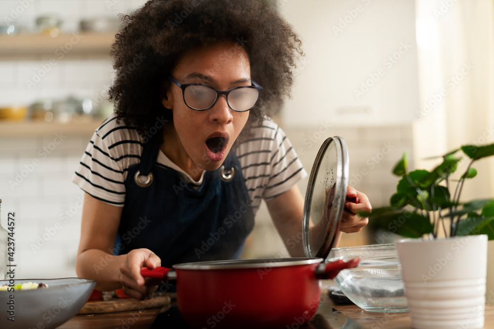 Beautiful woman with curly hair cooking at home. Young woman in kitchen Beautiful woman with curly hair cooking at home. Young woman in kitchen