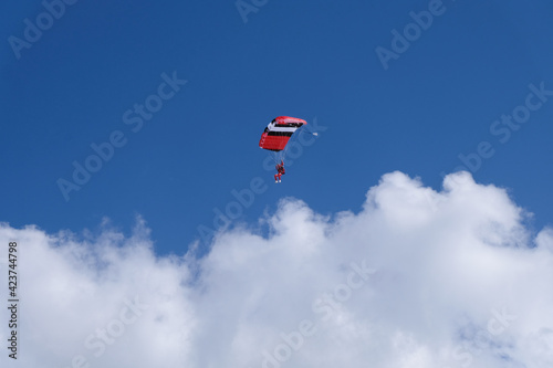 Skydiving. Parachutist flying over large white clouds