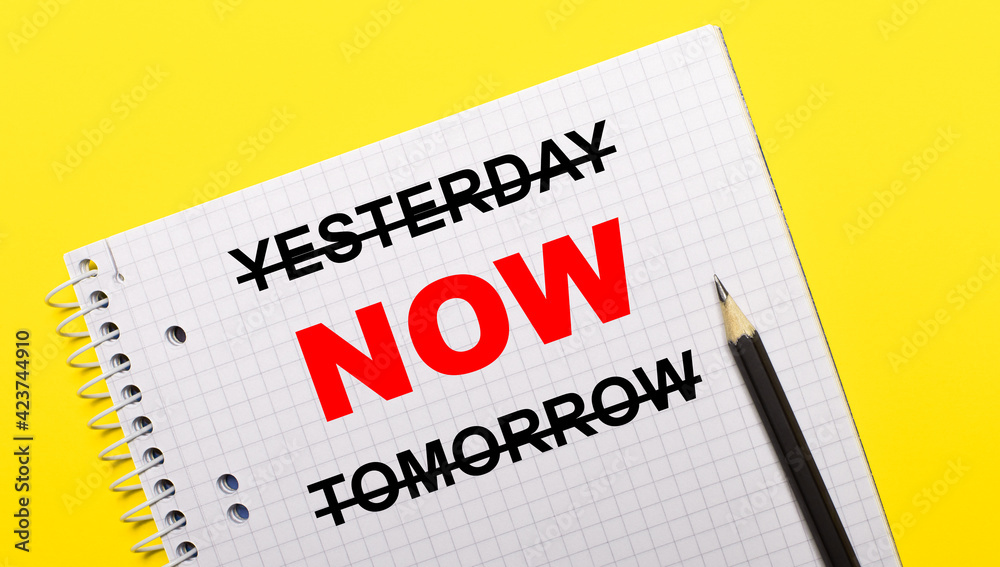 White notebook with inscription YESTERDAY NOW TOMORROW written in black pencil on a bright yellow background. White notebook with inscription YESTERDAY NOW TOMORROW written in black pencil on a bright yellow background.