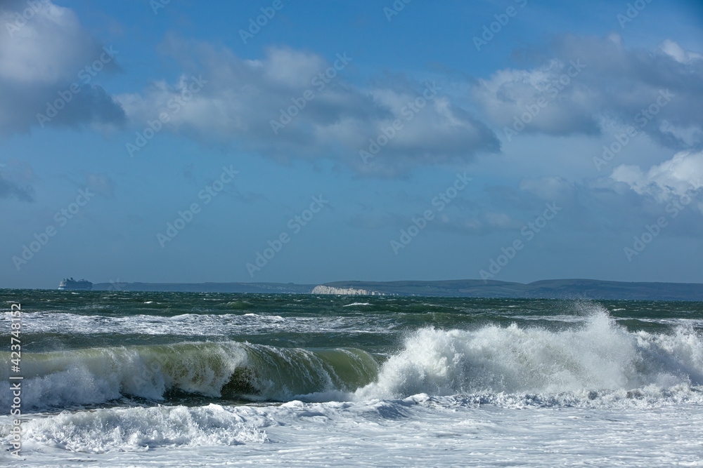 Stormy weather at the beach with crashing waves under a majestic blue sky